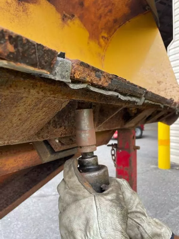 A close-up photo of a snowplow blade change in progress.